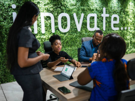 Young African businesswoman talking with a group of work colleagues during a meeting together around a table in an office boardroom