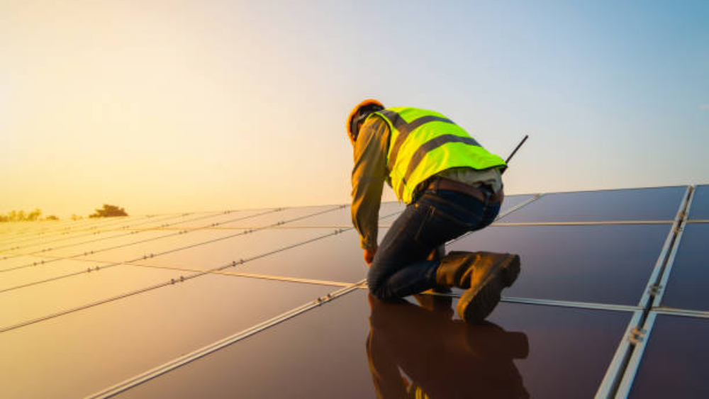 Portrait of engineer man or worker, people, with solar panels or solar cells on the roof in farm. Power plant with green field, renewable energy source in Thailand. Eco technology for electric power.