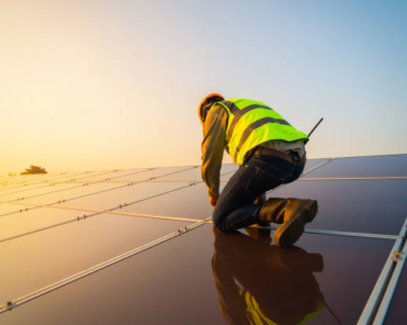 Portrait of engineer man or worker, people, with solar panels or solar cells on the roof in farm. Power plant with green field, renewable energy source in Thailand. Eco technology for electric power.