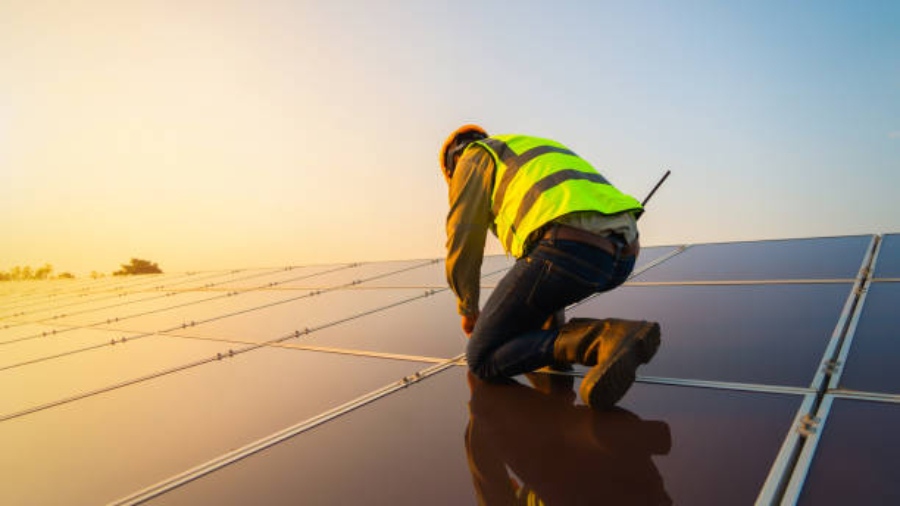 Portrait of engineer man or worker, people, with solar panels or solar cells on the roof in farm. Power plant with green field, renewable energy source in Thailand. Eco technology for electric power.